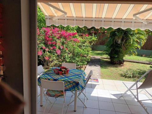 a table and chairs on a patio with flowers at Residence Corail in Sainte-Rose