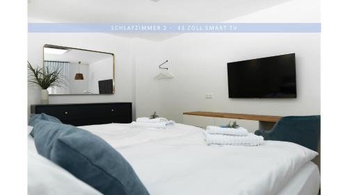 Dos camas en una habitación con un televisor en la pared. en Apartment Leinetal - bester Schlafkomfort in hochwertiger Hotelbettwäsche, 3 Zimmer - große Küche, Duschbad & Parkplatz, en Northeim
