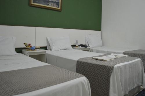 a room with three beds and a green wall at Hotel Cuca Fresca in Cotia