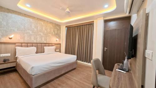 バラナシにあるHotel Ravindraya Residencyのベッドと机とテレビのある寝室