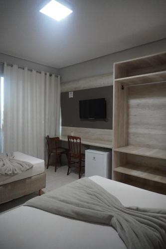 a bedroom with a bed and a dining room at Hotel Premium Uruçuí in Uruçuí