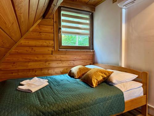 a bedroom with a bed with two pillows and a window at Drewniany zakątek - domek z sauną i balią in Międzybrodzie Bialskie
