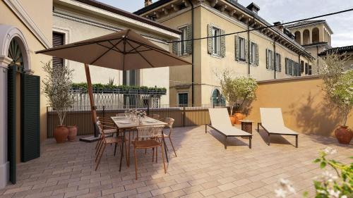 un patio avec une table, des chaises et un parasol dans l'établissement Homy Livia Verona, à Vérone