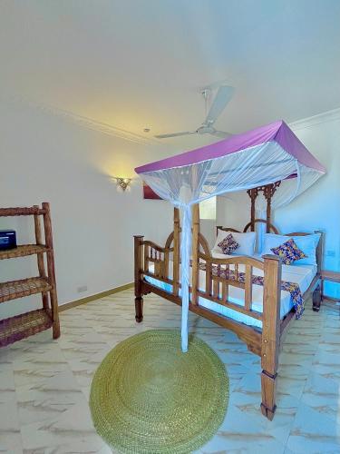 a bedroom with two beds with a canopy at Karibu House Paje in Paje
