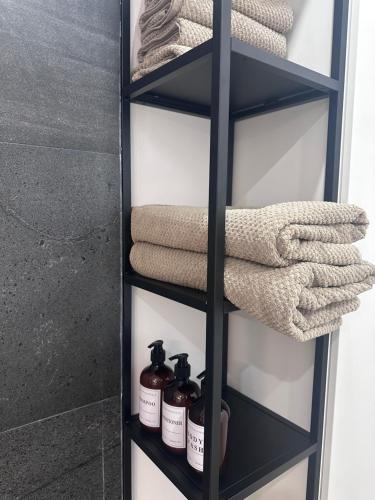 Un estante con toallas y productos de limpieza en un baño. en Madeira Home at Cliff Residence, en Santa Cruz