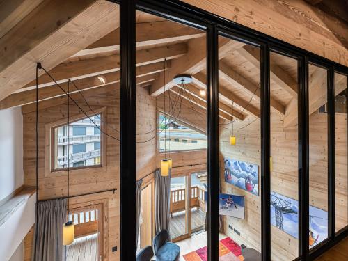 an attic room with wooden walls and a large window at Duplex de Charme à Courchevel Moriond, à Proximité des Pistes et Commodités - FR-1-563-57 in Courchevel