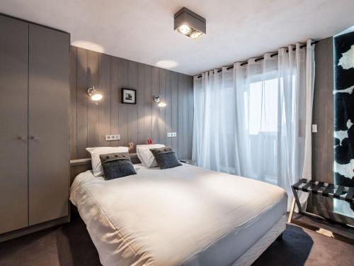 a bedroom with a large white bed with a window at Appartement Raffiné à Courchevel Moriond, 4 Étoiles, Près des Remontées Mécaniques - FR-1-563-99 in Courchevel