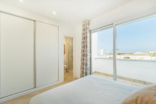 a bedroom with white walls and a large window at Lujoso chalet con jardín privado a 300 metros de la playa in Conil de la Frontera