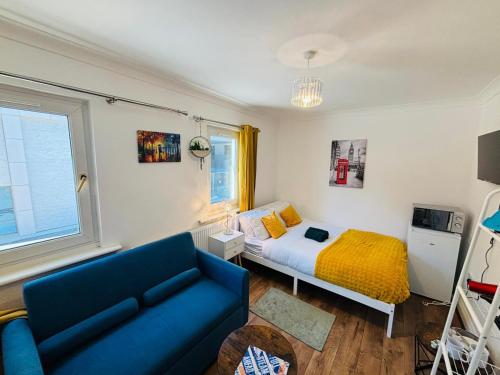 a living room with a bed and a blue couch at Royal Wharf Inn in London