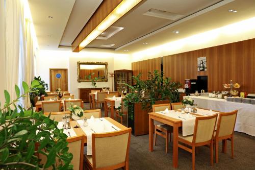 a restaurant with wooden tables and chairs and plants at Hotel Maxim in Svätý Jur