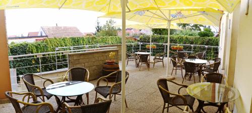 a patio with tables and chairs and an umbrella at Hotel Maxim in Svätý Jur
