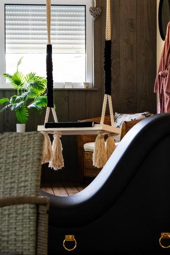 a swing in a room with a chair and a window at Charme & Sens Avec Jacuzzi intérieur in Thésée