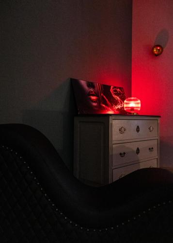 a bedroom with a bed and a dresser with a red light at Charme & Sens Avec Jacuzzi intérieur in Thésée