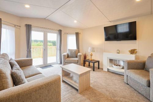 a living room with a couch and a tv and a fireplace at Host & Stay - Deer View Lodge in Pickering