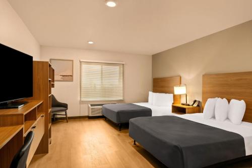 a hotel room with two beds and a flat screen tv at LivAway Suites Tri-Cities-Richland in Richland