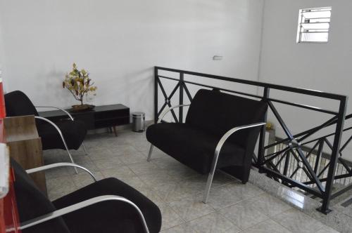 a living room with black chairs and a table at Hotel Cuca Fresca in Cotia