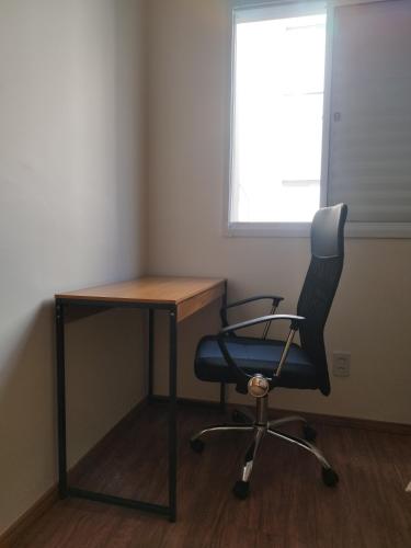 a desk and a chair in a room with a window at Apartamento novo e aconchegante! in Jaboticabal