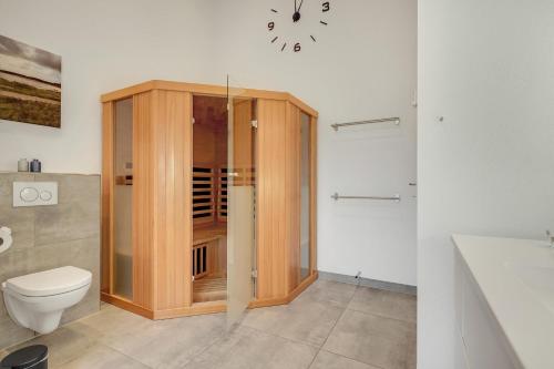 a bathroom with a wooden shower and a toilet at Hedevang 22 Houstrup in Nørre Nebel