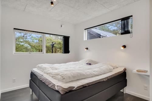 a bed in a room with two windows at Hedevang 22 Houstrup in Nørre Nebel