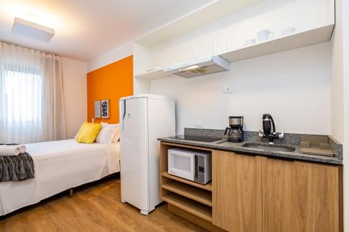 a kitchen with a refrigerator and a bed in a room at One House in Curitiba