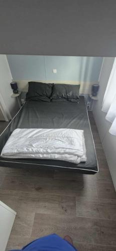 a bed in a small room with a bedsheet at mobile home camping la pignade in La Tremblade
