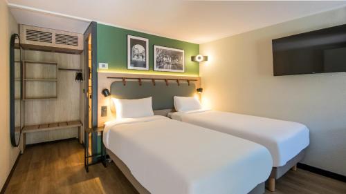 two beds sitting next to each other in a room at Campanile NATURE - Colmar Parc des Exposition in Colmar