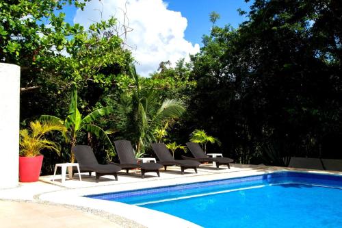 Spacious and elegant vacation home for 6 people in a private condominium في بلايا ديل كارمن: مجموعة من الكراسي تجلس بجوار حمام السباحة