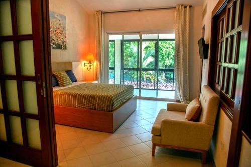 Spacious and elegant vacation home for 6 people in a private condominium في بلايا ديل كارمن: غرفة نوم بها سرير وكرسي ونافذة