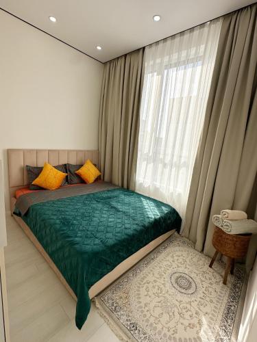 a bedroom with a green bed with a window at Apartments Жк Respublika новая евродвушка in Astana
