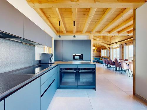 a kitchen with blue cabinets and a dining room at Chalet 5* avec spa, 15 pers., accès pistes direct - FR-1-267-310 in Villarembert