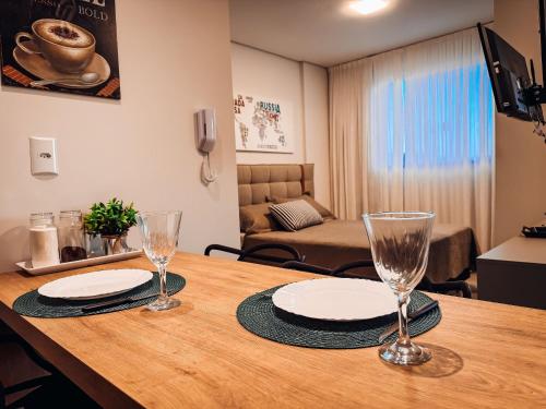 a wooden table with two plates and glasses on it at Flat Completo c/ Piscina e Garagem in Brusque