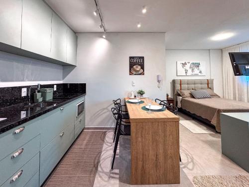 a kitchen and a living room with a bed at Flat Completo c/ Piscina e Garagem in Brusque