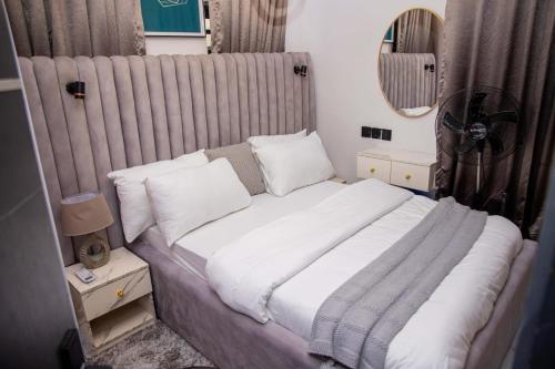 a bedroom with a large bed with white sheets and pillows at WHITNEY LUXURY APARTMENTs in Lekki