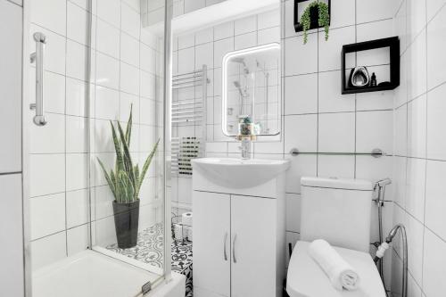 a white bathroom with a toilet and a sink at FREE parking - modern apartment in SW London in Merton
