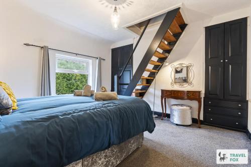 Un dormitorio con una cama azul y una escalera en Christina's House, en Oakamoor