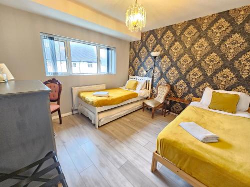 a bedroom with two beds and a table and chairs at St Georges house, Premium 3 bed Home Slough, Legoland, Windsor in Slough