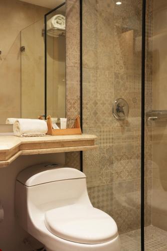 a bathroom with a toilet and a glass shower at Country International Hotel in Barranquilla