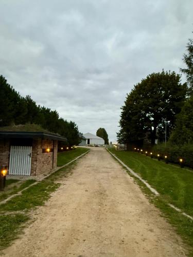 a dirt road with a barn and a building at DomkiTomki, Winnica Sindaco in Biskupice