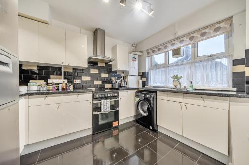 a kitchen with white cabinets and a washer and dryer at Comfortable and Modern 2-Bedroom Greenwich Apartment in London