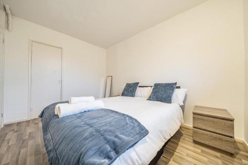 a bedroom with a large white bed with blue pillows at Comfortable and Modern 2-Bedroom Greenwich Apartment in London
