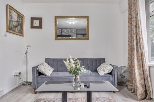 a living room with a blue couch and a table at Comfortable and Modern 2-Bedroom Greenwich Apartment in London