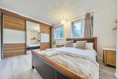 a bedroom with a large bed and a large mirror at Comfortable and Modern 2-Bedroom Greenwich Apartment in London