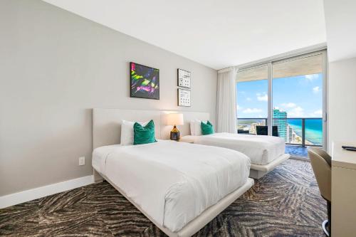 two beds in a room with a view of the ocean at Oceanfront Retreat Steps from Hollywood Beach in Hollywood Beach