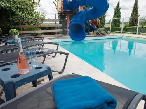 a swimming pool with a slide next to a table and chairs at Maswari en Drapeau in Lusignac
