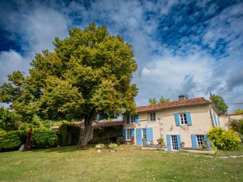 a large house with a tree in the yard at Maswari en Drapeau in Lusignac