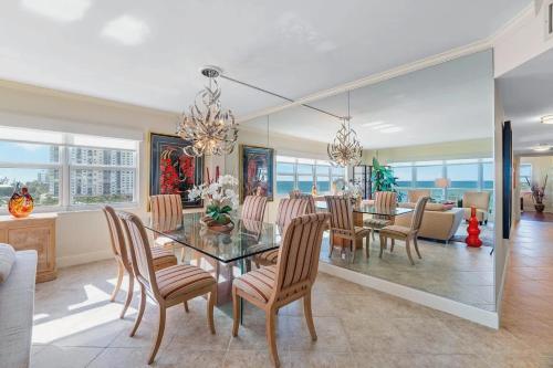 a dining room with a glass table and chairs at Oceanfront Three Bedroom Condo with Panoramic View in Pompano Beach