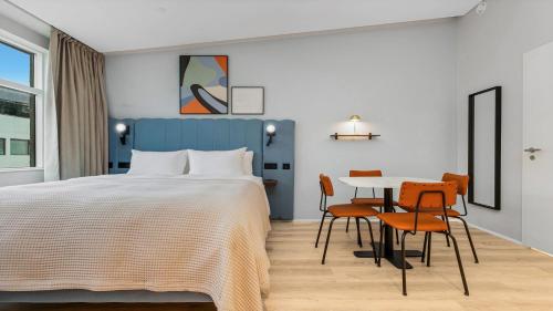 a bedroom with a bed and a table and chairs at Candlewood Suites Reykjavik by IHG in Reykjavík