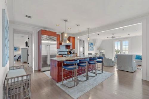 a kitchen and living room with blue bar stools at Elegant Three Bedroom Condo Near Rosemary Beach in Rosemary Beach