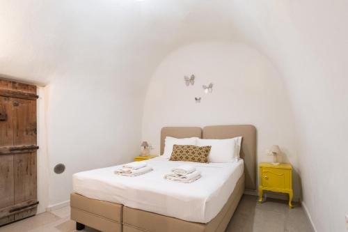 a bedroom with a bed with white sheets and a yellow table at Mantilida Villa in Emporio Santorini