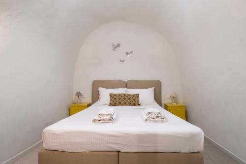 a bedroom with a white bed with two yellow night stands at Mantilida Villa in Emporio Santorini